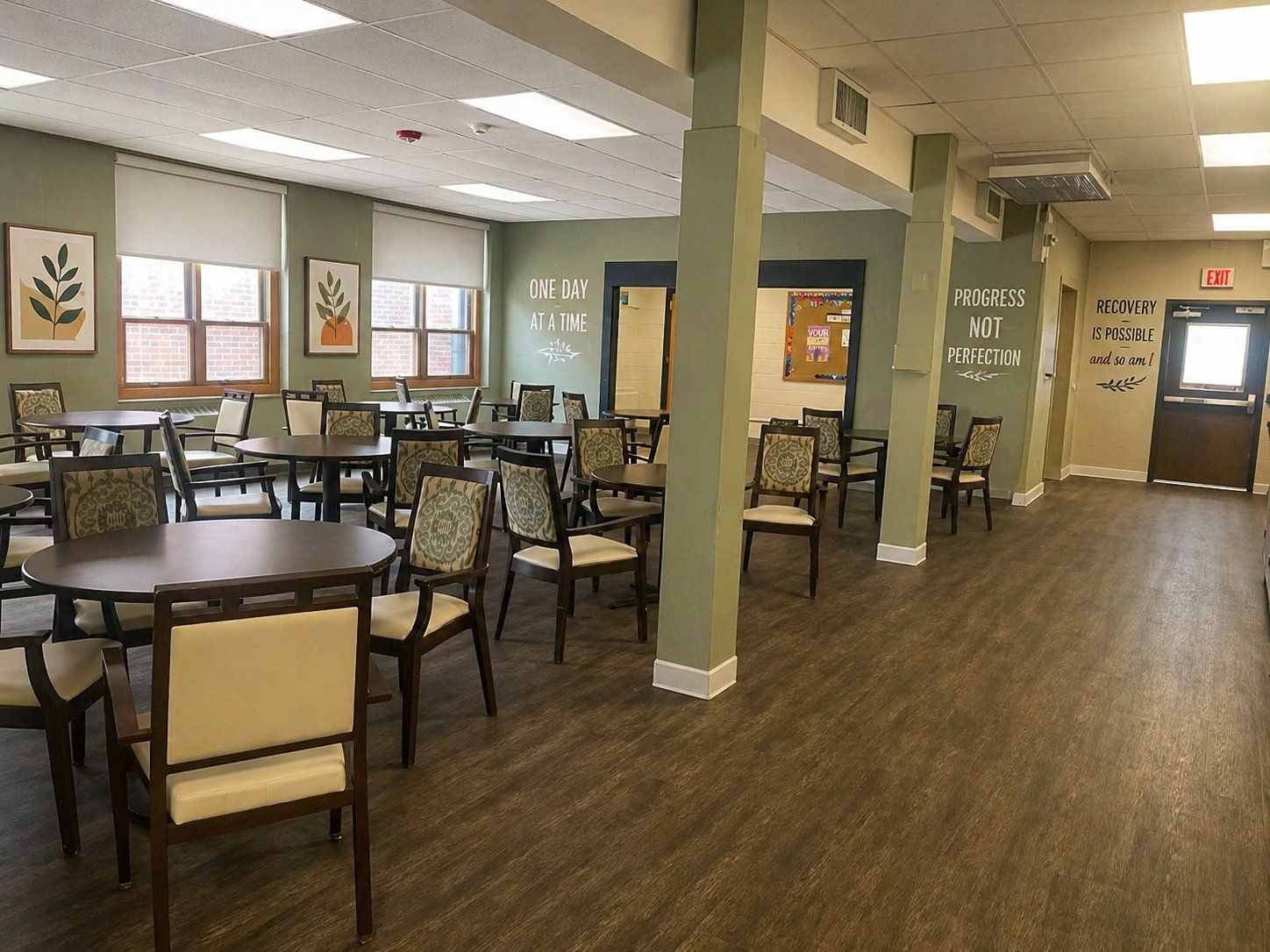 The dining and common room at Olympia Grove Recovery, with round tables and recovery quotes on the walls