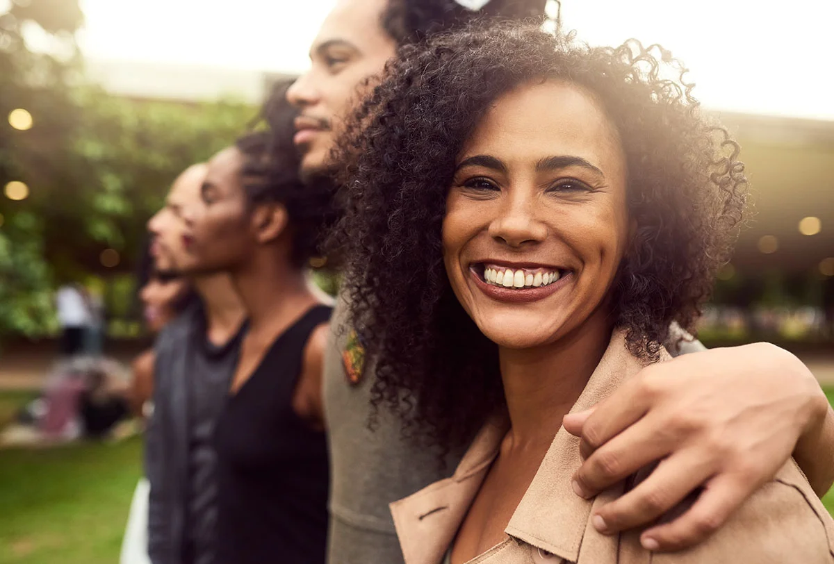 smiling woman stands outside with a group of people