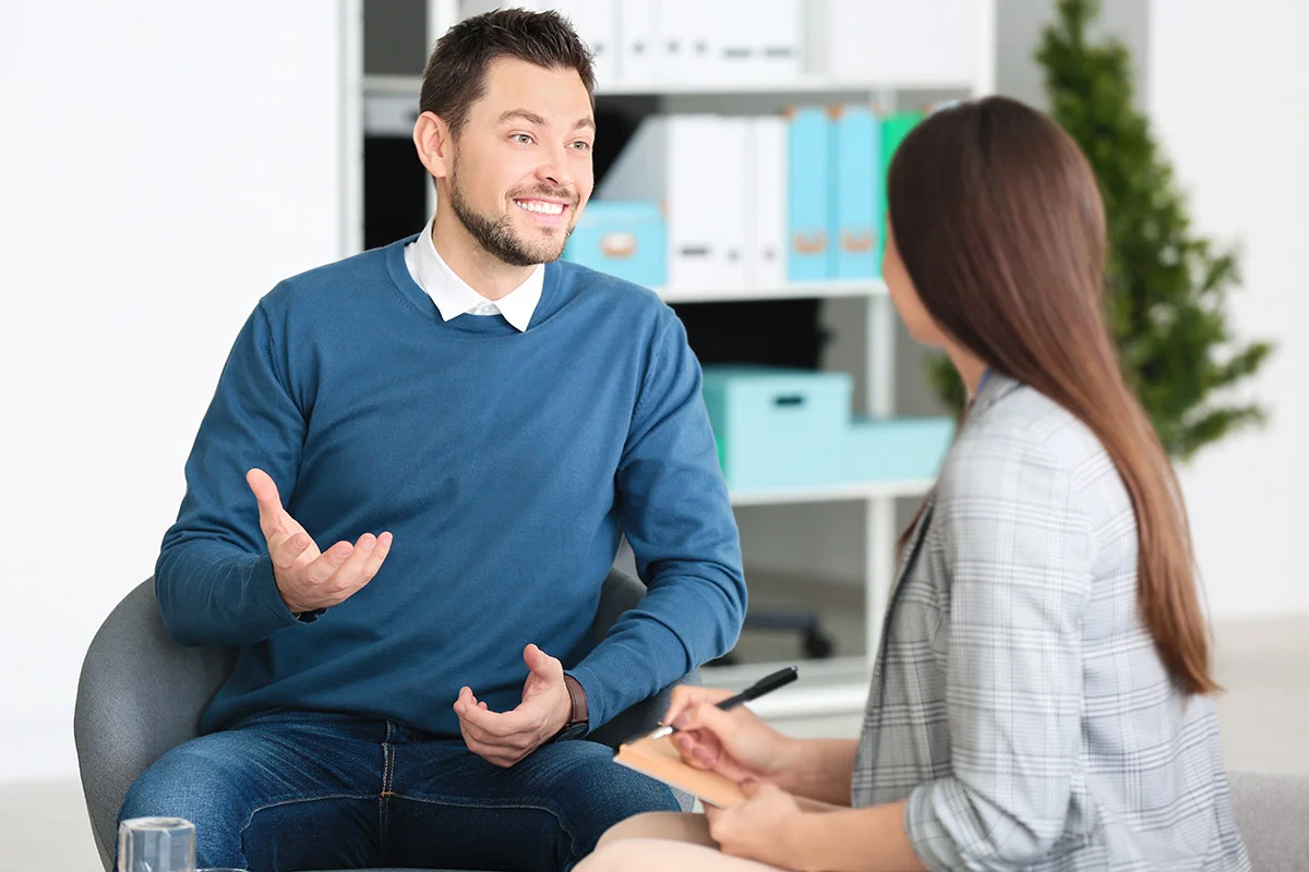 smiling man sits in chair talking to his therapy about how beneficial medical detox was