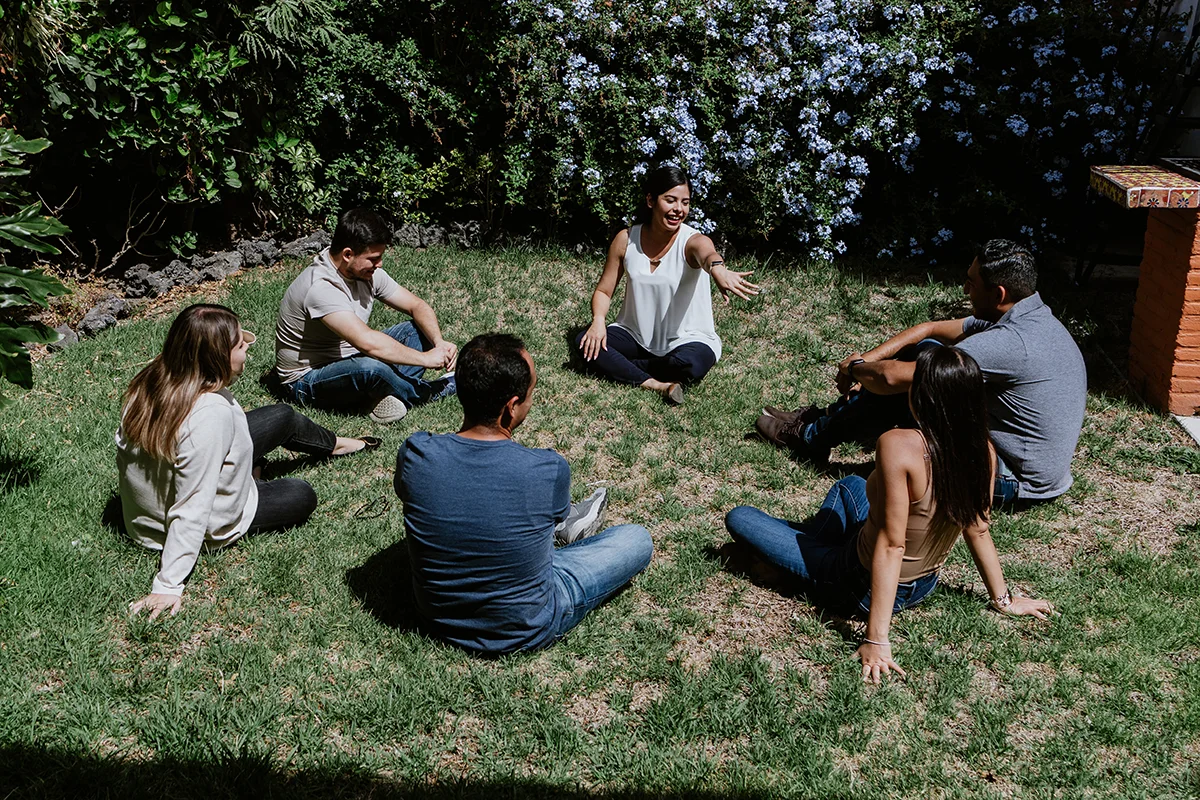 A co-ed group sit together in a circle outside. They are participating in group therapy at Olympia Grove Recovery in Ohio.