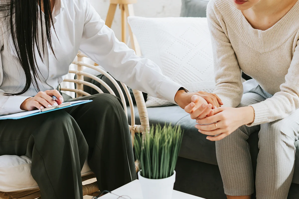A woman is holding the hand of her therapist. She is participating in rehab for addiction at Olympia Grove Recovery.