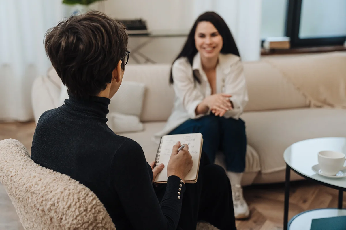 A woman sits across from her therapist on a couch. She is in substance use disorder treatment at Olympia Grove Recovery.