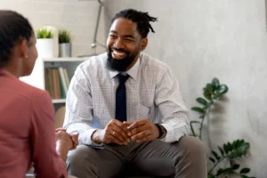 smiling man in a suit sits and talks to his therapist in relapse prevention therapy session